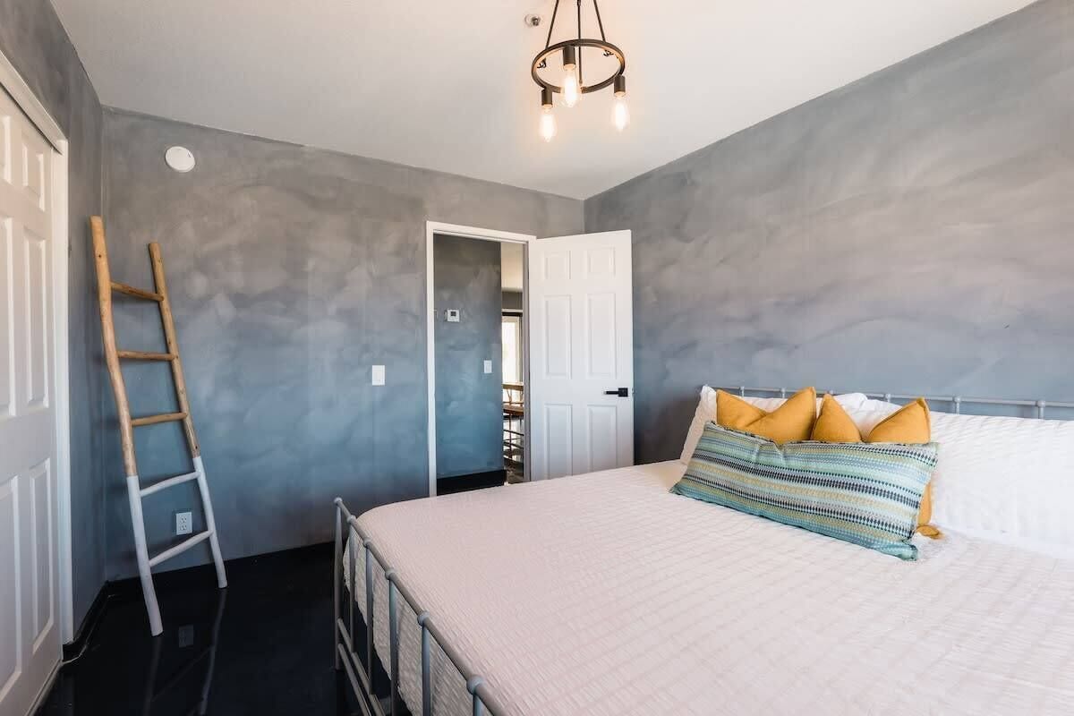 A bedroom with a bed, a ladder, and a door leading to a closet.