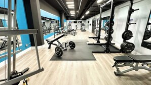 A gym with various exercise equipment, including weight benches and squat racks. - Luxury Studio Apartment Near McCormick Place & Soldier Field (Chicago)