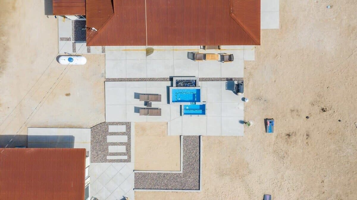 An aerial view of a hotel with a swimming pool, outdoor seating, and a covered patio area.
