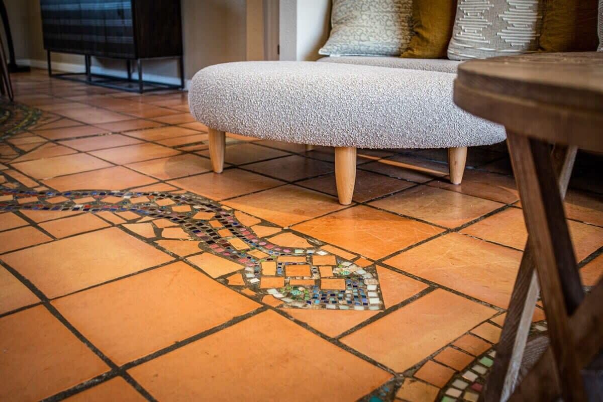 Un suelo de baldosas con diseño, un sofá y muebles de madera al fondo.