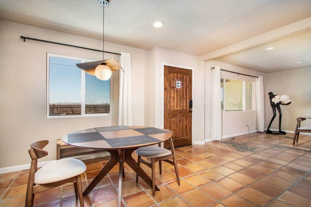 A dining area with a round table, chairs, and a pendant light.