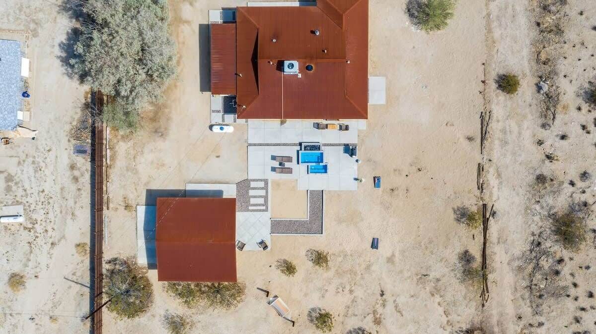 An aerial view of a property with a large central building, a smaller attached structure, and a swimming pool.