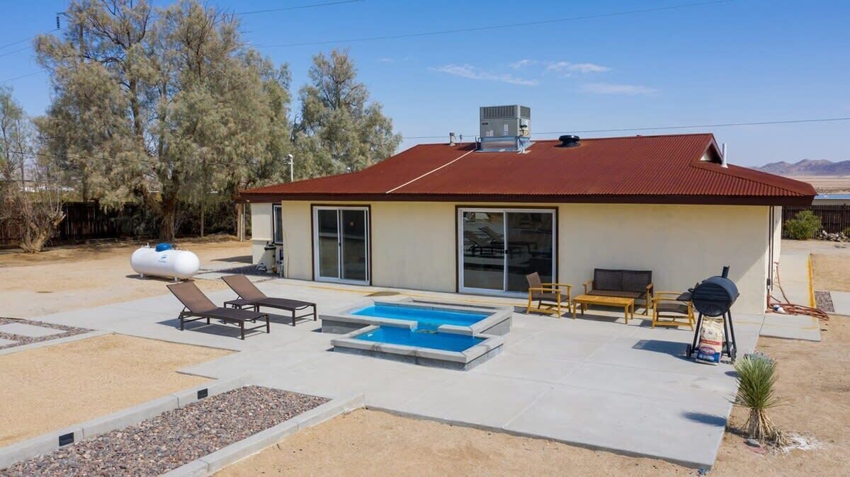A single-story house with a swimming pool, outdoor furniture, and a barbecue grill.