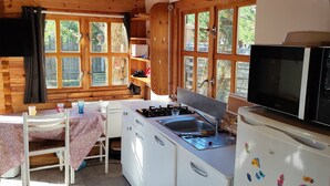 Une cuisine compacte avec des poutres en bois, un réfrigérateur blanc, une cuisinière et un four à micro-ondes.
