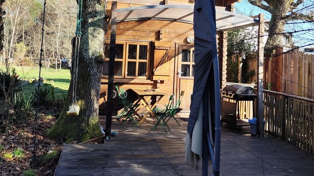 Une cabane en bois dotée d’une terrasse, entourée d’arbres.