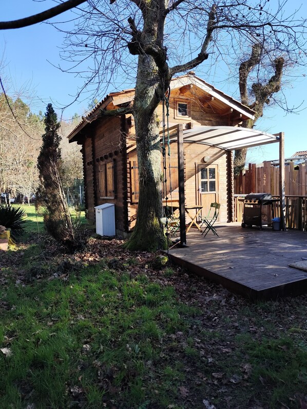 A wooden cabin with a covered patio, a small shed, and a fenced yard. - Small chalet in the Landes region, close to the lake, ocean and Dune du Pilat. (Sanguinet)