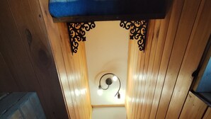 Un escalier étroit en bois, avec un banc sur le côté gauche et un mur orné d’un motif en forme de cœur.
