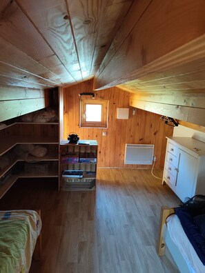 A compact, wooden-paneled room with bunk beds, a small window, a radiator, and a white cabinet. - Small chalet in the Landes region, close to the lake, ocean and Dune du Pilat. (Sanguinet)