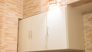 A white wardrobe with two doors and a handle, set against a wall with a stone pattern. - 360 Leme Beach Anchieta By SUHCasa (Rio de Janeiro)