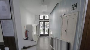 A narrow hallway with a fire extinguisher mounted on the wall, a door at the end, and a window with a view of the outside. - 360 Leme Beach Anchieta By SUHCasa (Rio de Janeiro)
