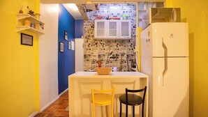 A compact kitchen with a white refrigerator, two chairs, a small island, and a blue accent wall. - 360 Leme Beach Anchieta By SUHCasa (Rio de Janeiro)