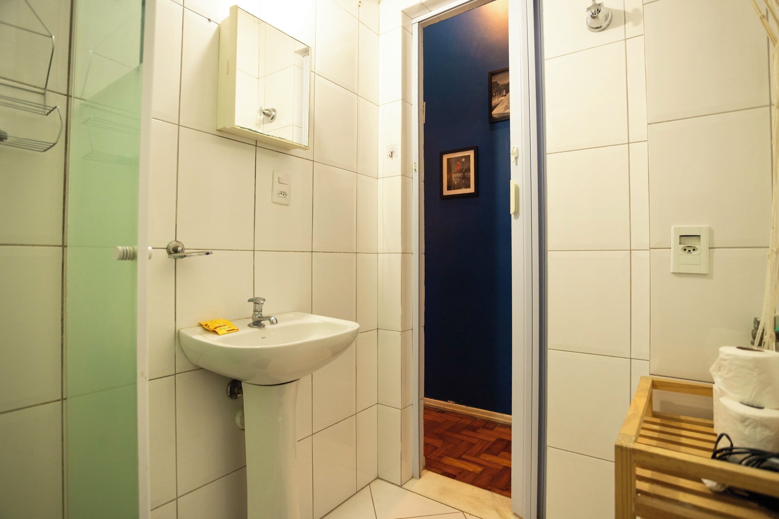A bathroom with a white sink, a mirror, and a wooden bench.