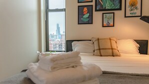 Una cama bien hecha con vistas a la ciudad, una ventana y cuadros en la pared.