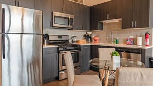 Una cocina moderna con electrodomésticos de acero inoxidable, armarios de madera oscura y una mesa de comedor de vidrio.