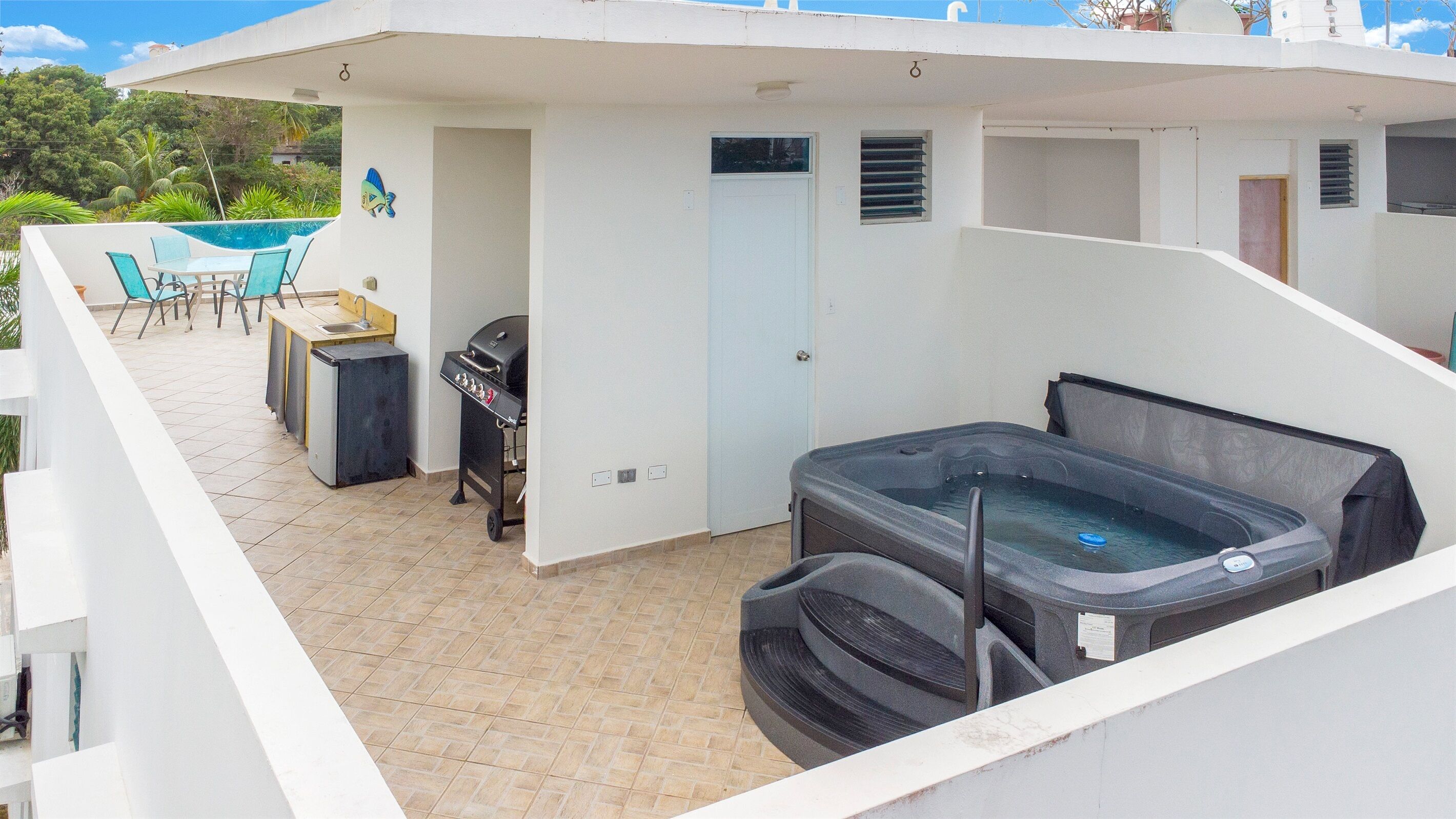 A rooftop patio with a hot tub, a grill, and a pool table.