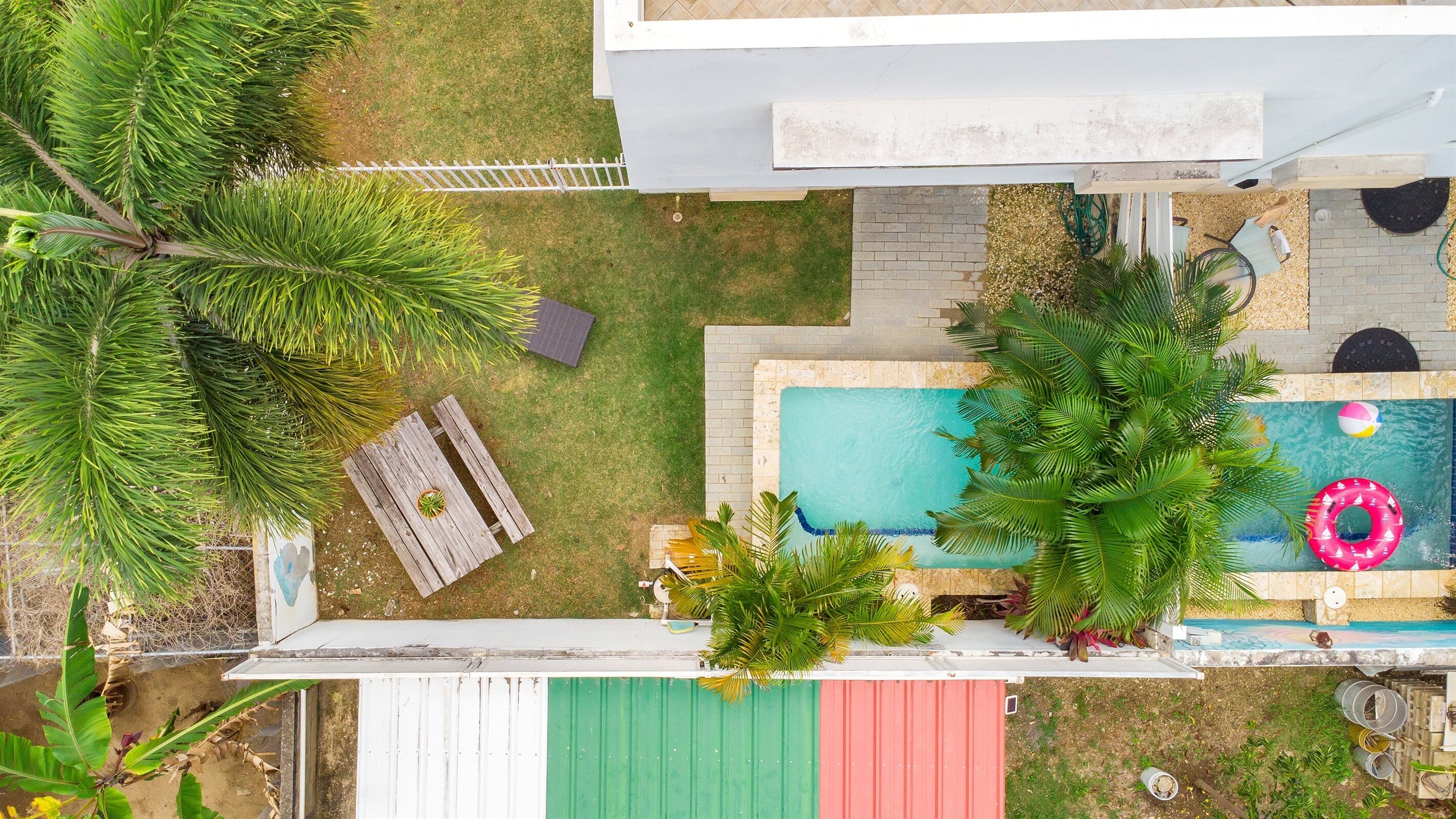Une piscine sur le toit, dotée d’une terrasse en bois, entourée de plantes tropicales et agrémentée d’une petite table avec une chaise.
