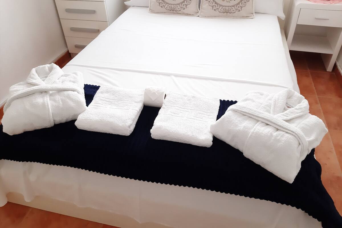 Een keurig opgemaakt bed met witte handdoeken en een donkerblauwe deken.
