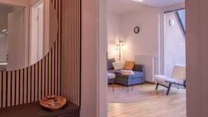 Un salon moderne avec un canapé, un fauteuil, une petite table et un miroir.