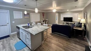 A spacious living area with a kitchen island, dining table, and seating. - ♥ of SSI Bungalow 2, Quick walk to beach and food ☼ (St. Simons Island)