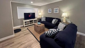 A living room with a TV, two couches, a coffee table, and a ceiling fan. - ♥ of SSI Bungalow 2, Quick walk to beach and food ☼ (St. Simons Island)