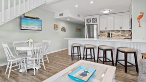 A modern kitchen with white cabinets, a stainless steel refrigerator, and a wooden backsplash.