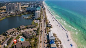 An aerial view of a coastal resort with beachfront properties, a marina, and a large hotel complex.
