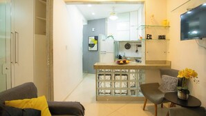 A modern kitchen with a central island, a dining area with a table and chairs, and a living room with a sofa and cushions. - 360 Aterro do Flamengo By SUHCasa (Rio de Janeiro)