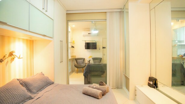 A modern hotel room with a large bed, a seating area with a chair and table, and a glass partition separating the room from the bathroom. - 360 Aterro do Flamengo By SUHCasa (Rio de Janeiro)