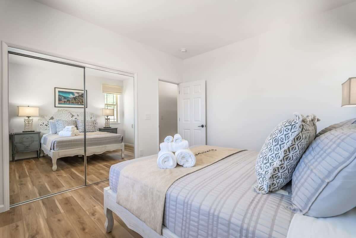 Quarto com cama, mesa de cabeceira, espelho e porta.