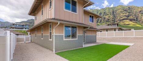 A two-story house with a front yard and a gravel driveway.