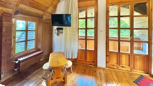 Un intérieur en bois avec une télévision, un fauteuil et de grandes fenêtres.