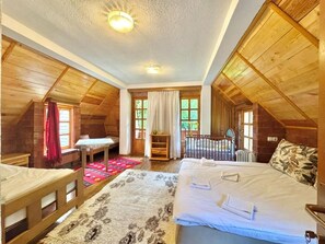 Un dormitorio acogedor en el ático con paredes de madera, una cama grande, un escritorio y una ventana con cortinas.