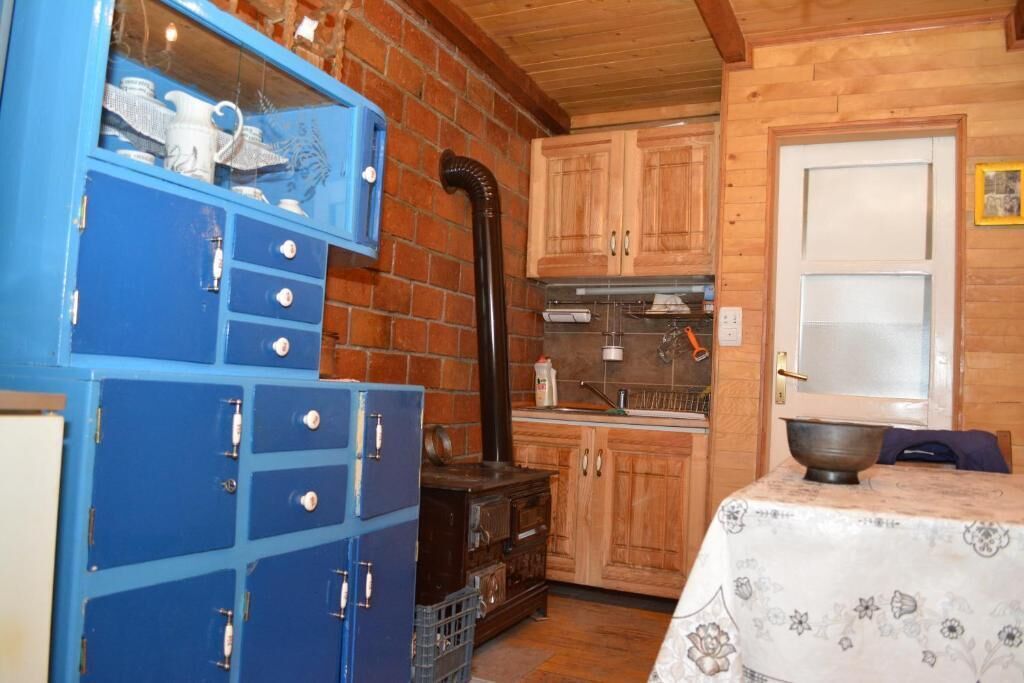 A rustic kitchen with wooden cabinets, a blue storage unit, and a stove.