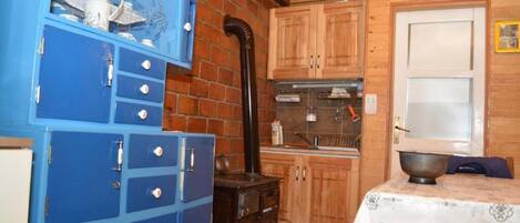 A rustic kitchen with wooden cabinets, a blue storage unit, and a stove.