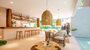 A modern bar area with wooden stools, wicker pendant lights, and a bar counter with shelves of bottles. - Marakame San Pancho (San Francisco)