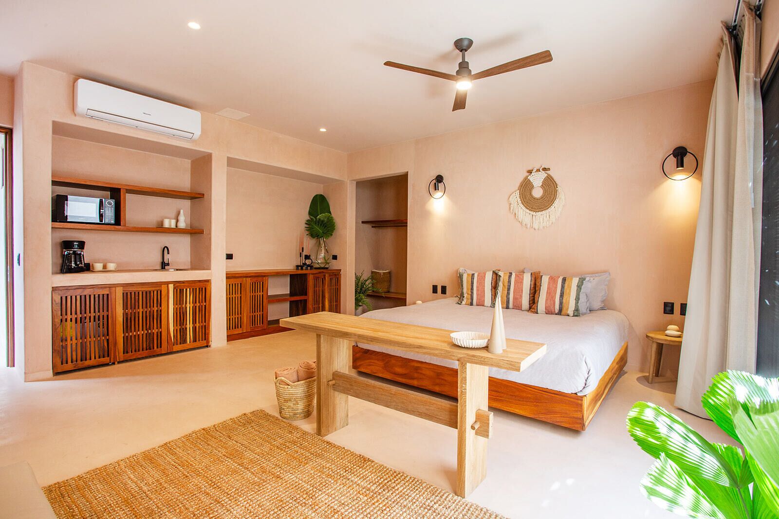 Une chambre à coucher avec un lit, des meubles en bois, un ventilateur de plafond et une petite table.