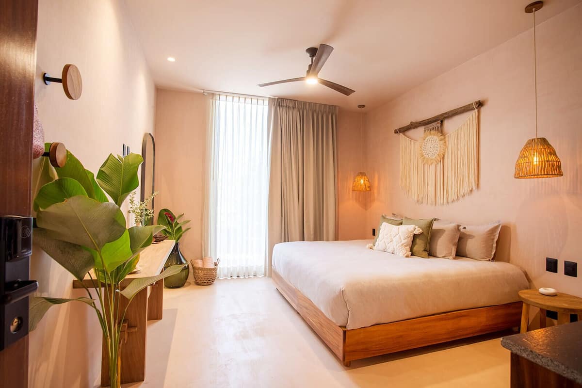 A modern bedroom with a large bed, a ceiling fan, and a window with curtains.