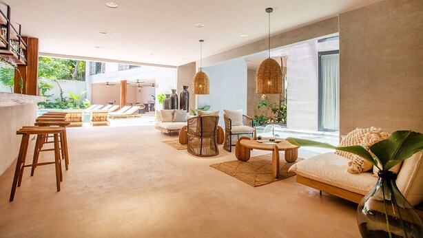 A spacious living area with a sofa, chairs, a coffee table, and a bar area with stools. - Marakame San Pancho (San Francisco)
