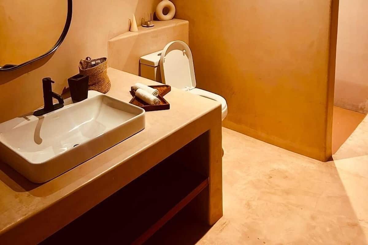 A modern bathroom with a large mirror, a white sink, and a toilet.