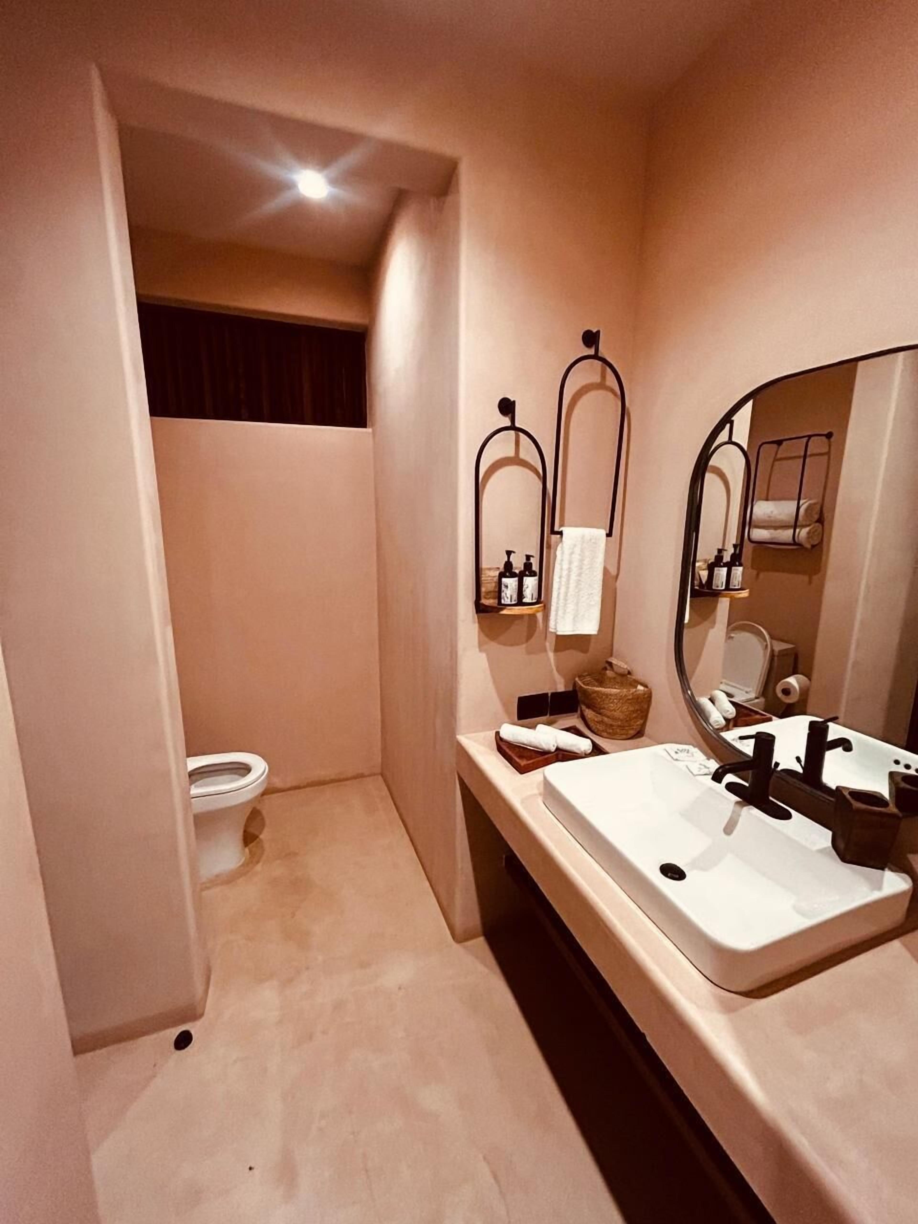 A modern bathroom with a toilet, a sink with a mirror, and a towel rack.