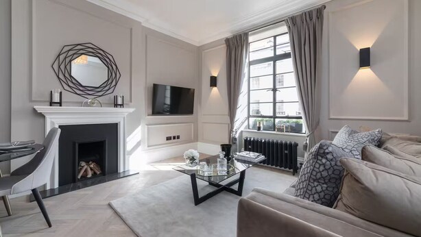 A modern living room with a fireplace, a sofa, a coffee table, and a TV mounted on the wall.