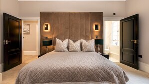 A large bed with a quilted headboard, two bedside lamps, and a nightstand.