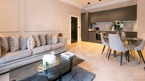 A modern living room with a sofa, coffee table, and dining area with chairs.