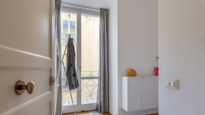 A room with a sliding glass door leading to a balcony, a white cabinet, and a yellow object on top.