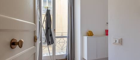 A room with a sliding glass door leading to a balcony, a white cabinet, and a yellow object on top.