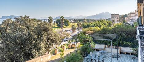 Terraza en la azotea con vistas a un paisaje urbano, incluyendo edificios y una cadena montañosa distante.