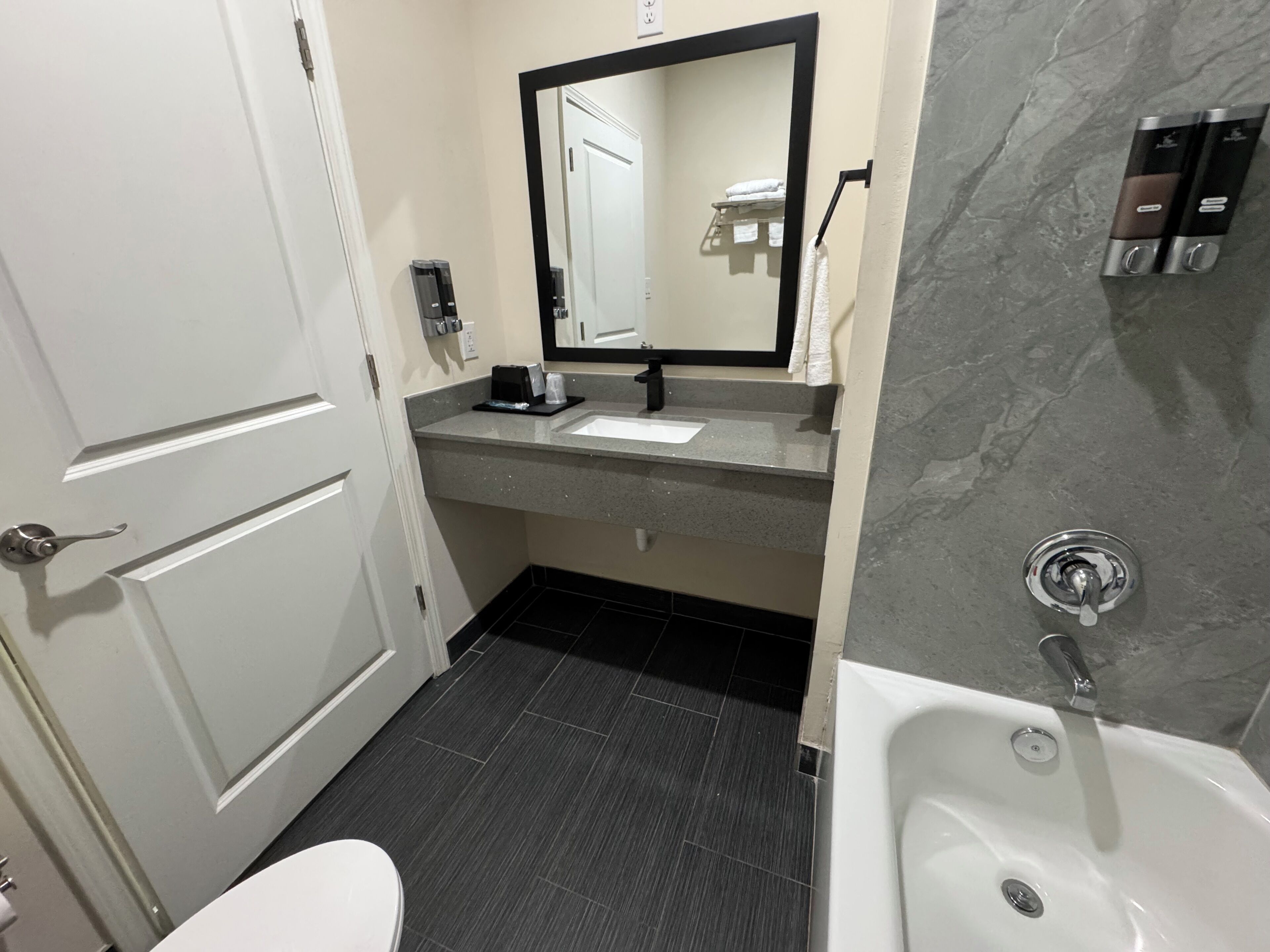 A bathroom with a white toilet, a sink with a mirror above it, and a bathtub.