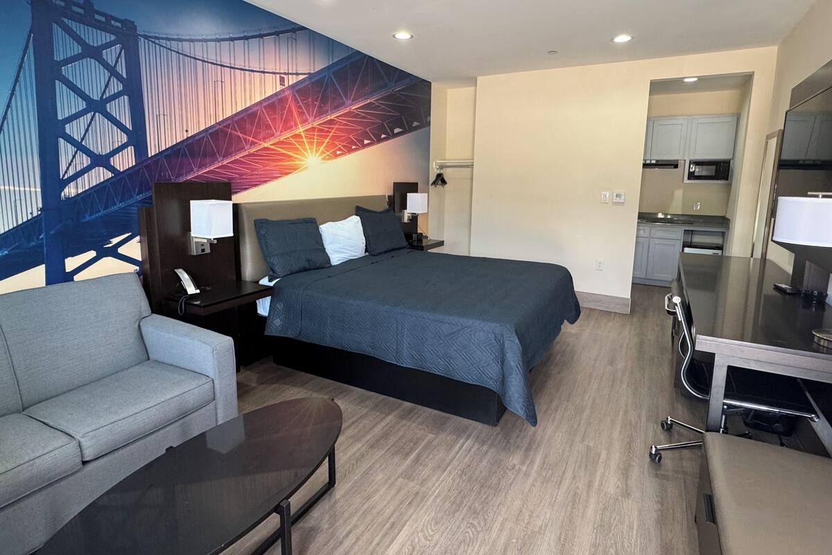 Una habitación de hotel moderna con cama, escritorio, silla y kitchenette.