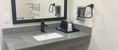 Un baño moderno con un espejo grande, un lavabo y un cubo de basura.