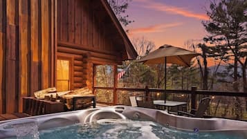 Eine Holzhütte mit Whirlpool und Sitzgelegenheit im Freien.